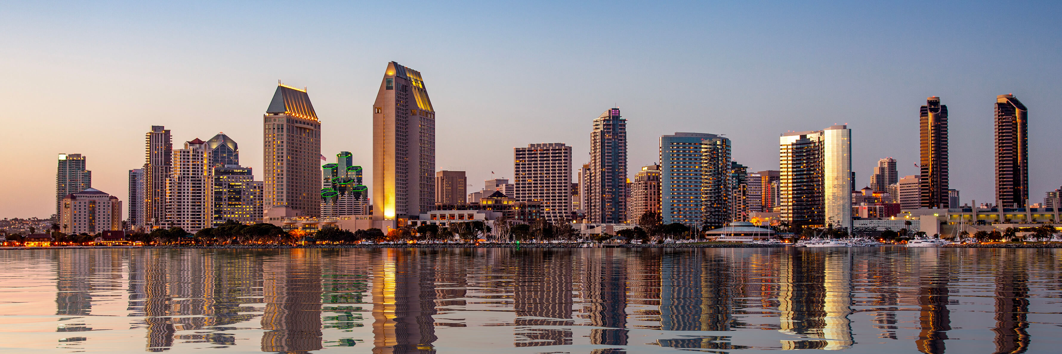 Sunset illuminating the tall skyscrapers of San Diego in California from Centennial Park in Coronado with artificial water reflection.